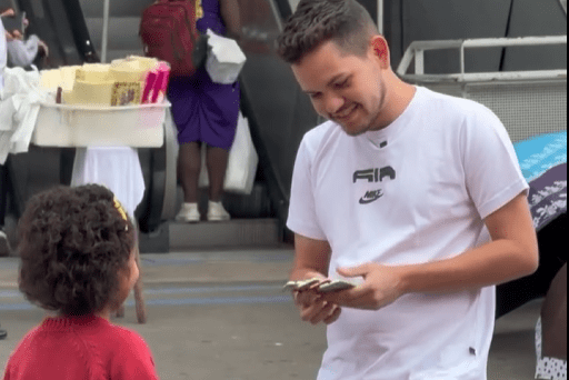 Menina vende balas em frente à estação de trem de Osasco enquanto conversa com um homem, em um momento de reconhecimento, empatia e valorização do esforço infantil em meio à rotina urbana.